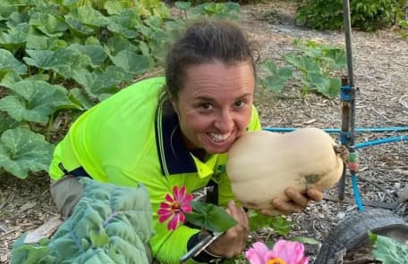 A woman holding a pumpkin in her garden
