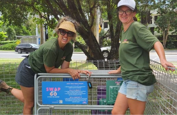 Two women in front of a compost collection point
